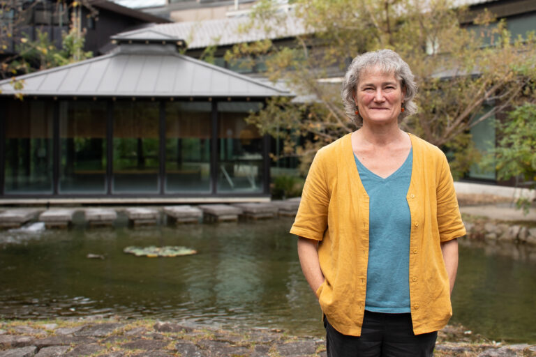 A picture of Janet Dwyer in front of a small lake and japanese building