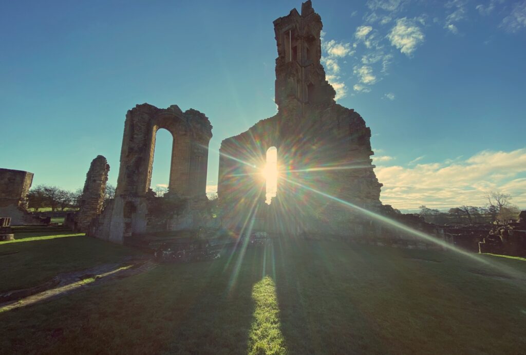 A derelict abbey with the sun shining through