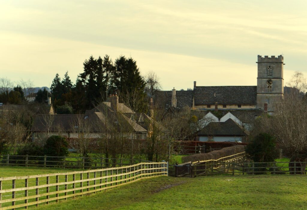 A church tower and houses with fields in the foreground